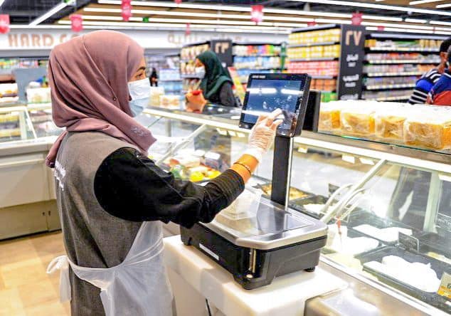 A Saudi female employee serves a customer at a hypermarket, newly launched by the operator LuLu and run by a team of women, in the Saudi Arabian port city of Jeddah, on February 21, 2021. (Photo by Amer HILABI / AFP)